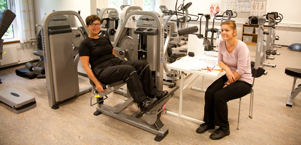 I »maskinrummet«, der er indrettet i tidligere patientstuer på Brovst Sygehus, er Karin Duedahl fra Skovsgaard i gang med fysisk træning under vejledning af fysioterapeut Signe Christensen. Foto: Ejgil Bodilsen